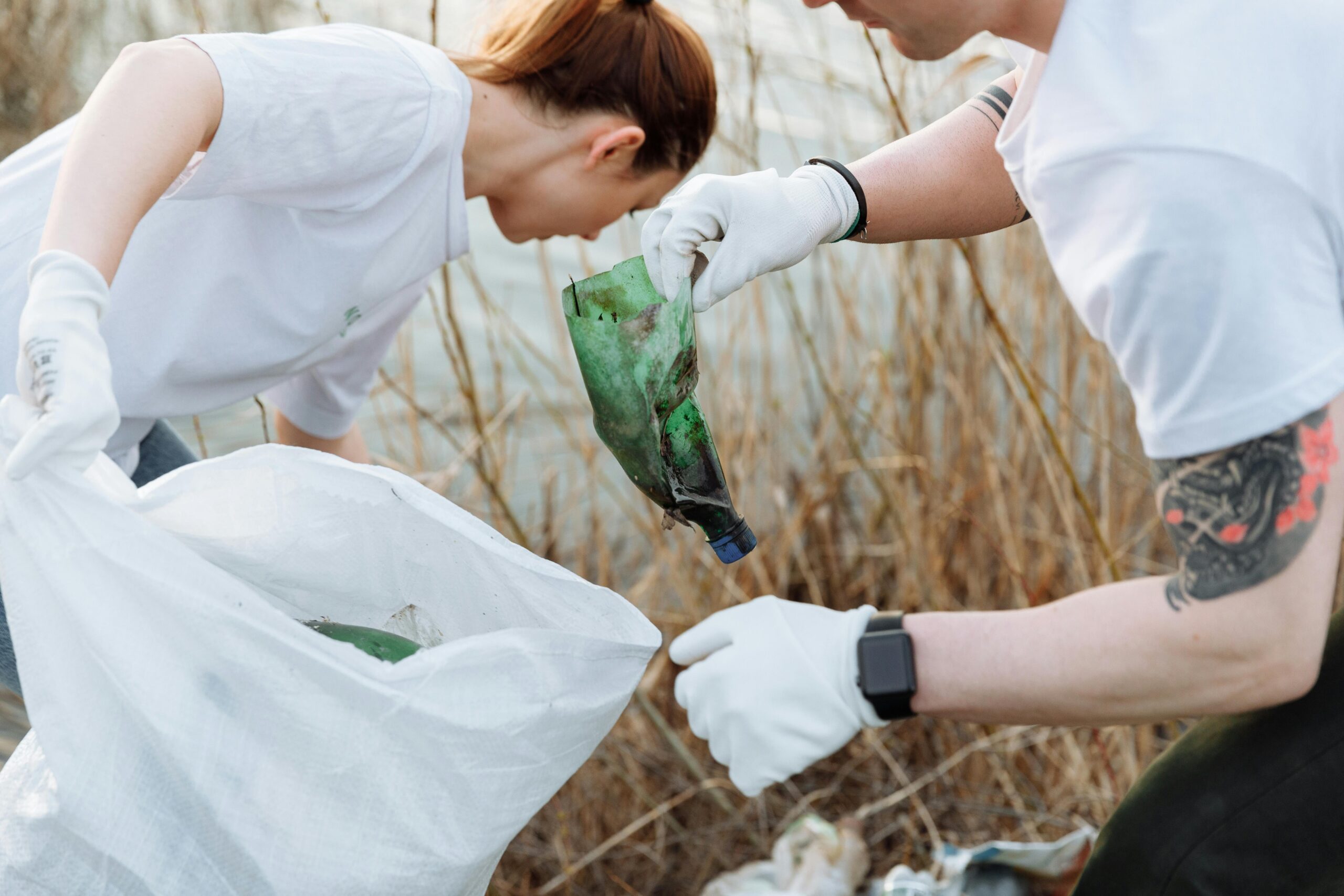 Two volunteers picking up litter outdoors to promote environmental awareness.